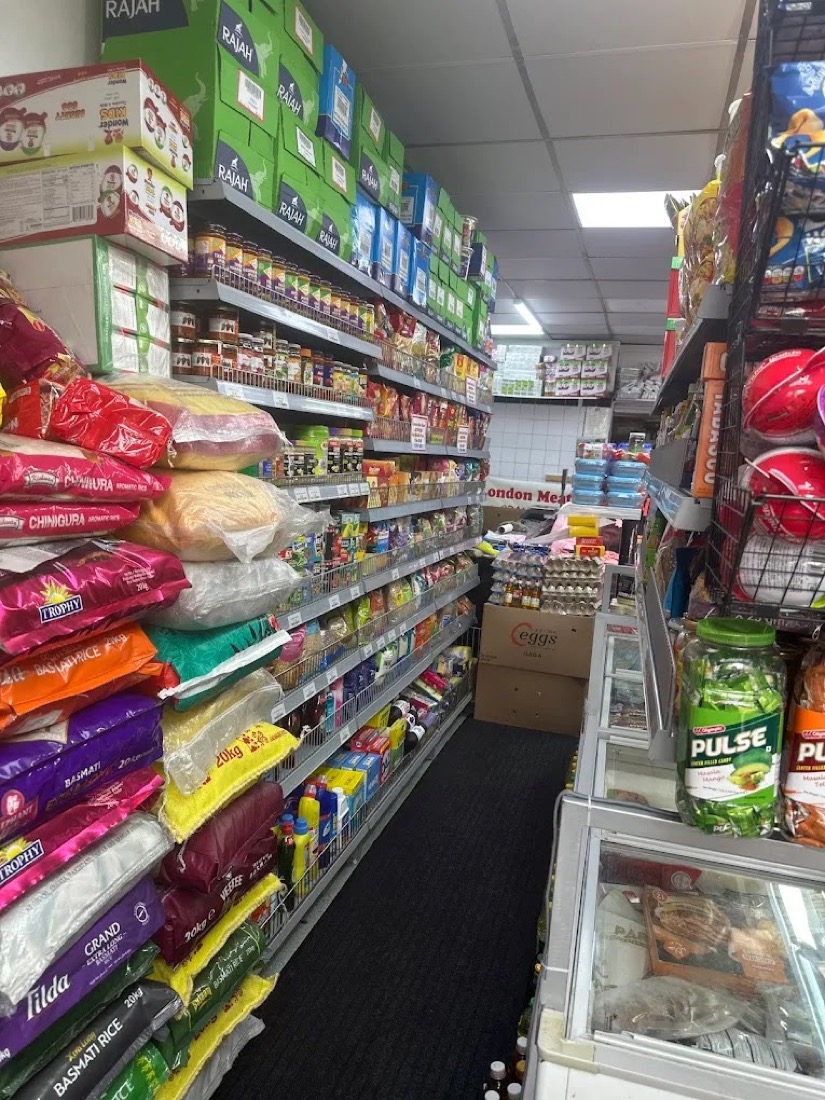 Packed grocery aisle inside London Meat Bazar, with rice, spices and tinned goods on the shelves